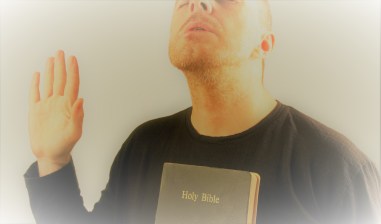 man makes a prayer with the Bible and with his hand raised
