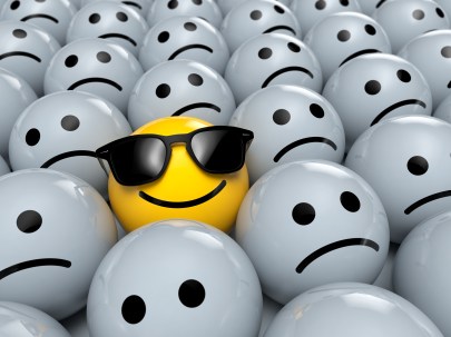 Happy Smiley Emoticon mit Sonnenbrillen zwischen traurigen Emoticons