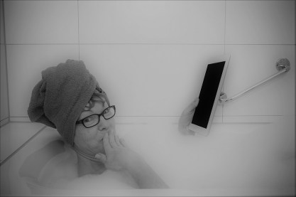 Confused woman in bathtub with tablet computers