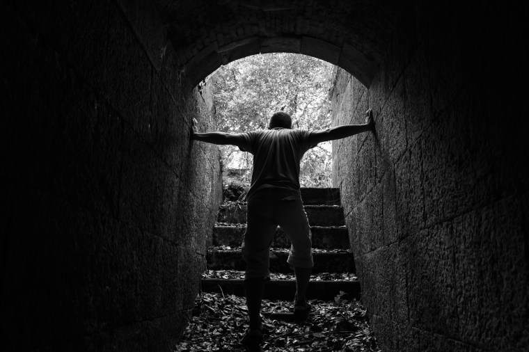 Tired man goes out of dark stone tunnel