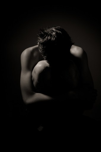 Young Man Huddling on Floor Holding Knees to Chest