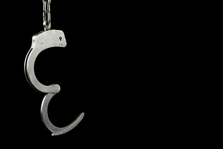 Open police handcuffs on a black background with text / writing / copy space