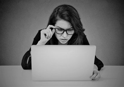 Worried woman working on laptop looking confused at computer screen