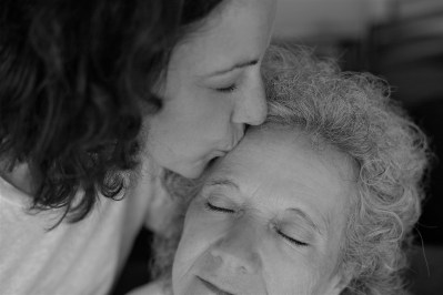 Adult daughter kissing elderly mother