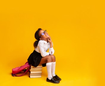 Elementary School Girl Dreaming Sitting On Stack Of Books